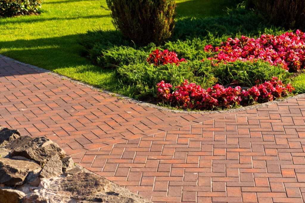 Path from red paving slab next to flowers