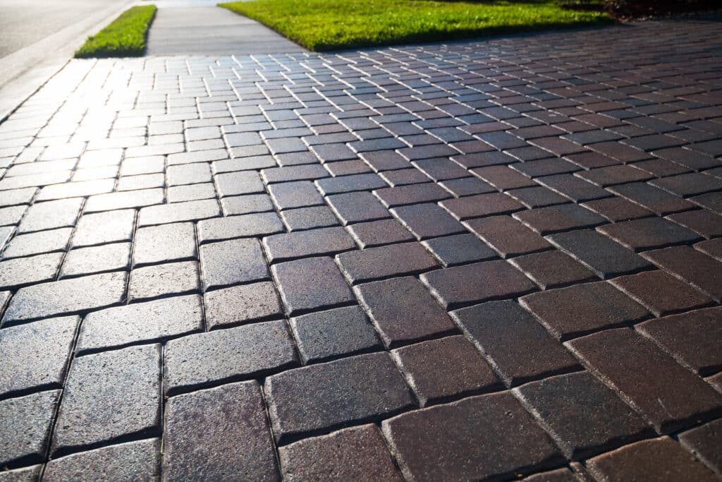 Close up showing driveway sealant to protect the bricks. Sealcoating background for new home construction.